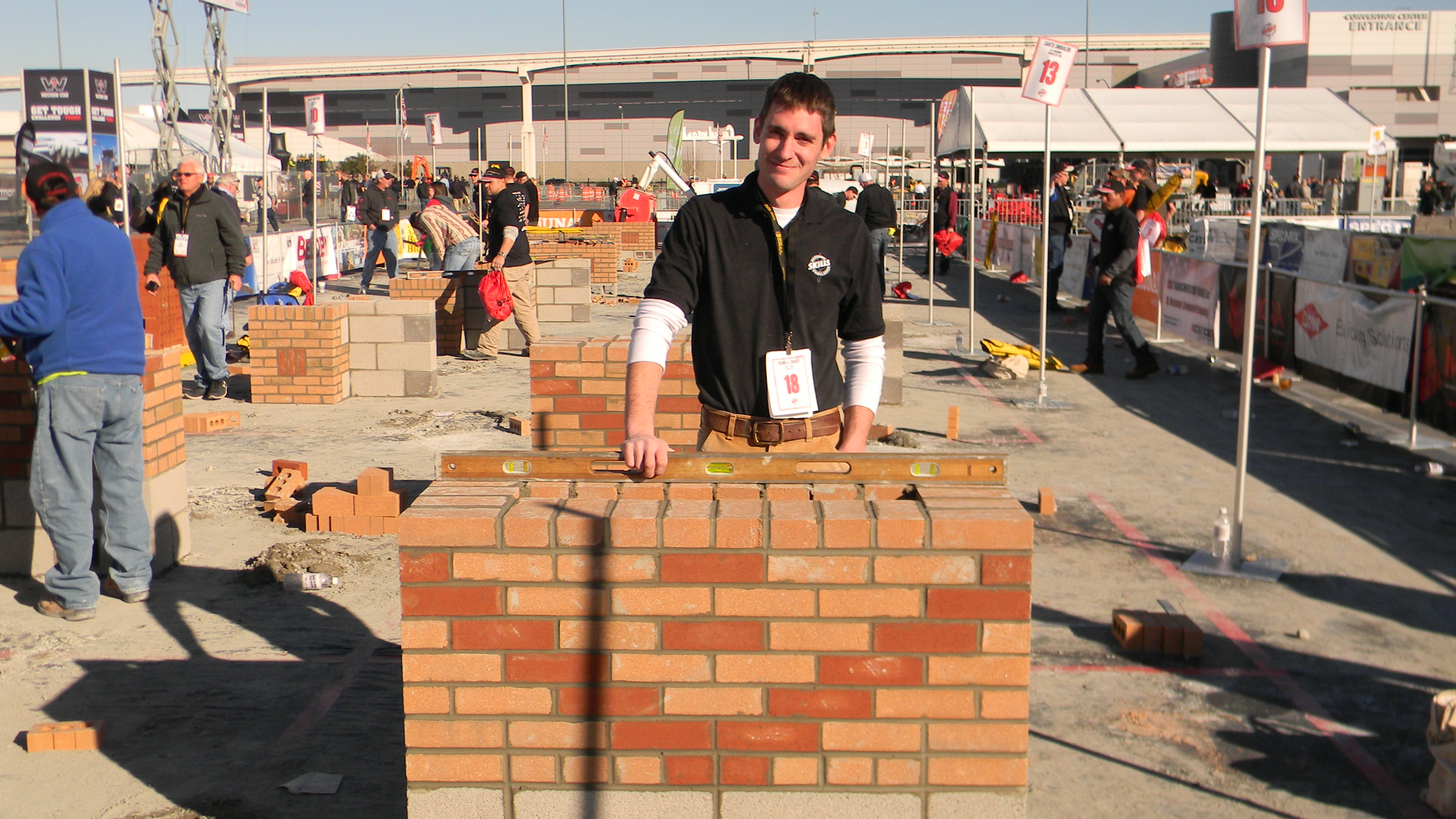Nick Bracy stands with a hand on the short brick wall that he layed during the competition.